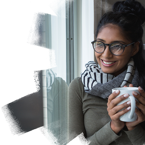 Indian women with a mug watching outside the window and smiling