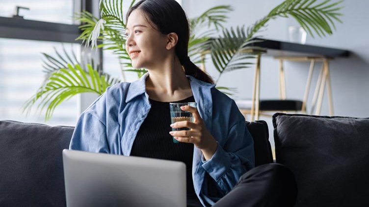 Women sitting with a laptop and glass of water in other hand