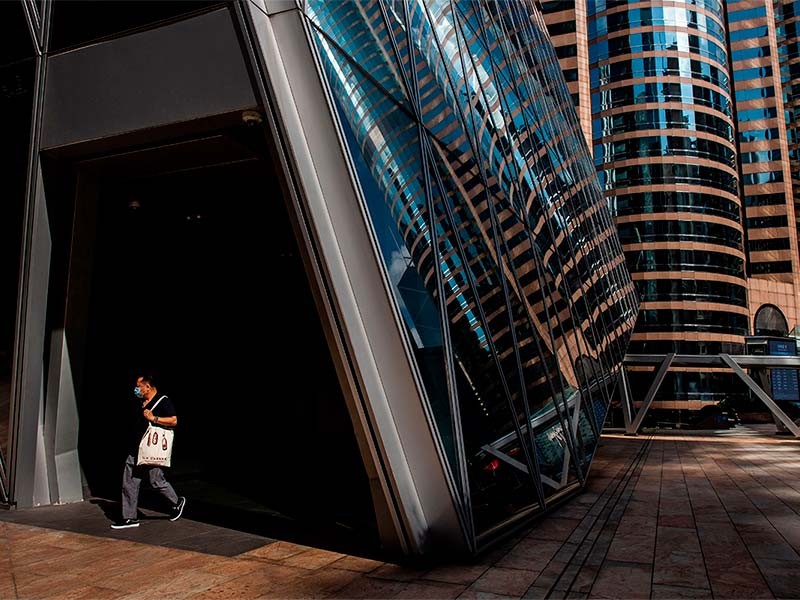 Man wearing mask and walking besides the real estate office building