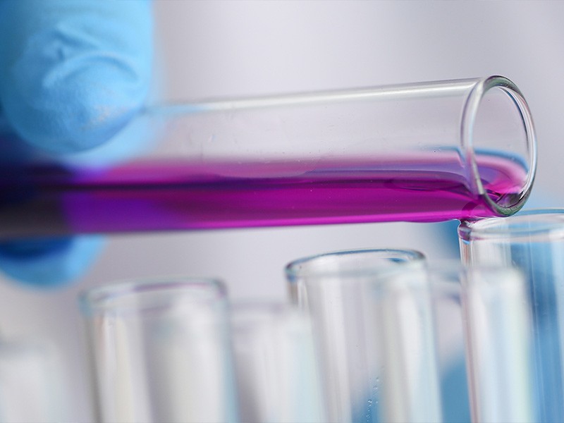 Medical researcher adding a chemical liquid to a test tube during their research in a medical laboratory