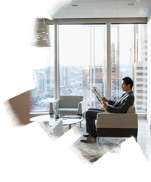 Businessman seated on a sofa, reading a newspaper in the office reception area
