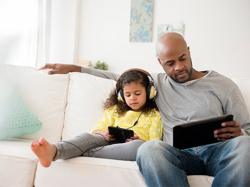 A man sitting with his daughter and looking at tablet