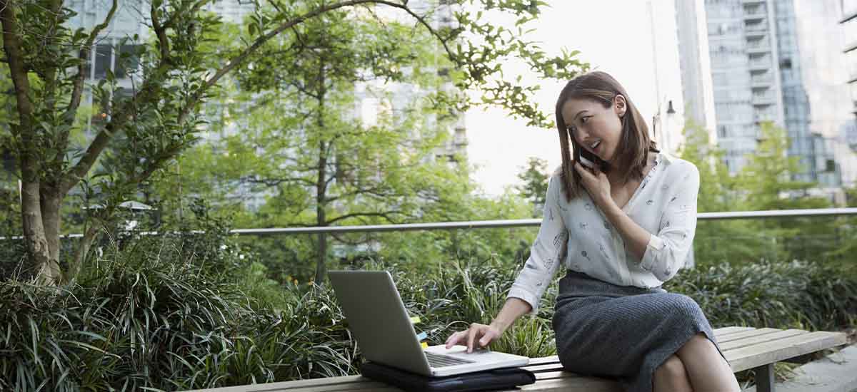 A girl talking over mobile and looking laptop 